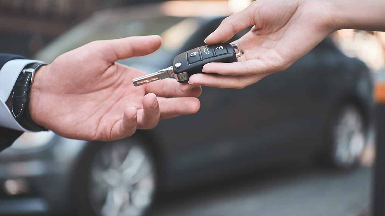 Car dealership.Young man receiving car key from saleswoman.