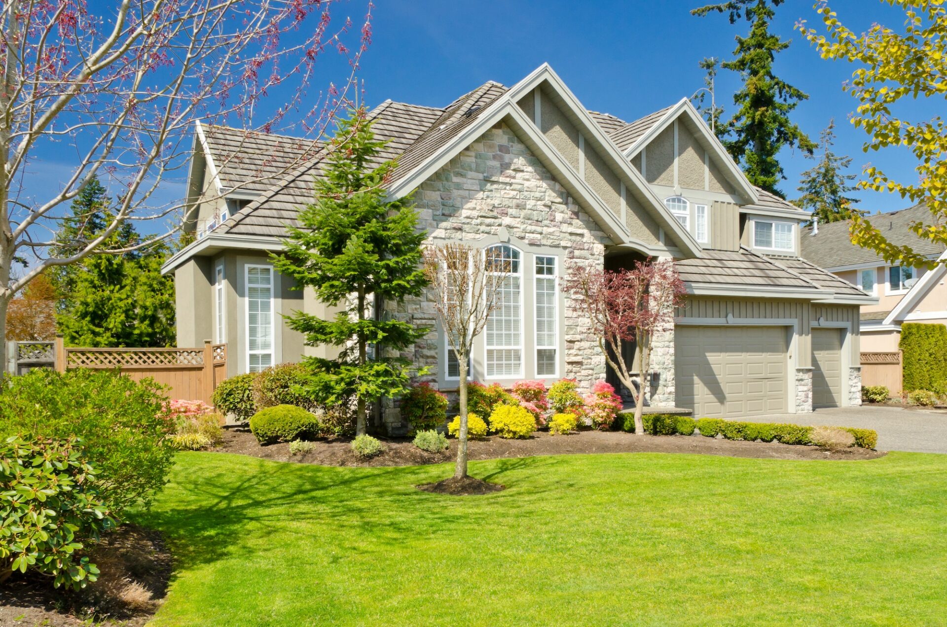 Beautiful beige brick house on a sunny day with a green freshly cut yard.