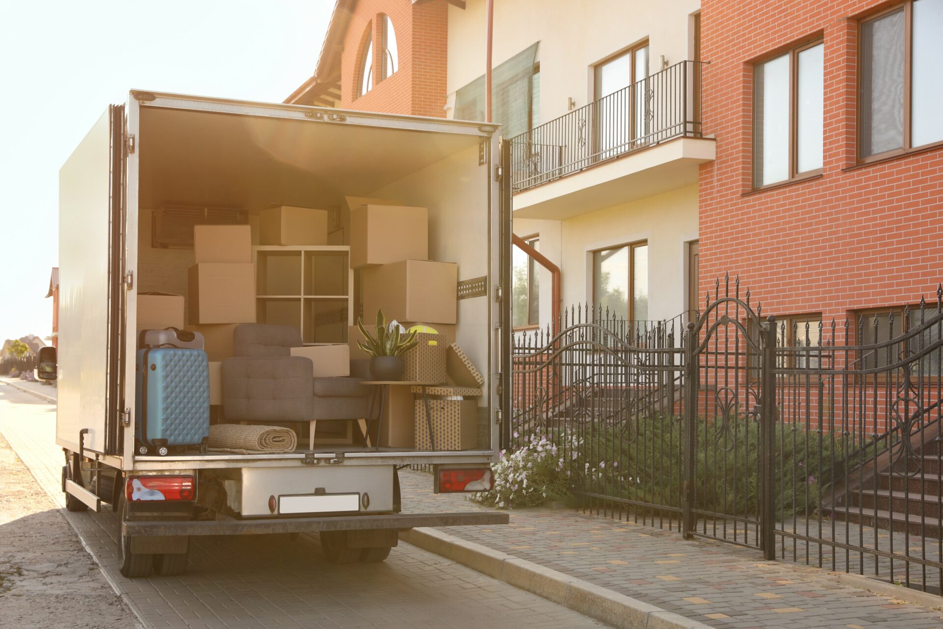 Van full of moving boxes and furniture near row of townhomes.