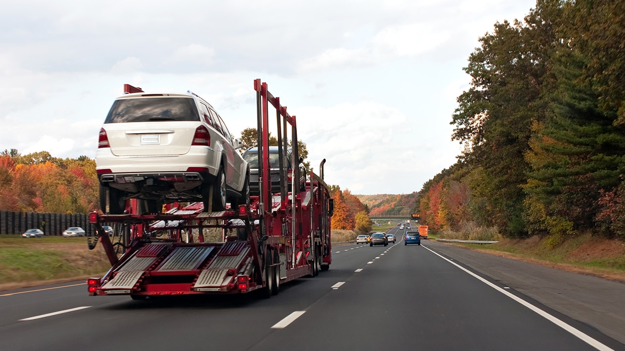 An automotive car carrier truck driving down the highway with a full load of new vehicles.