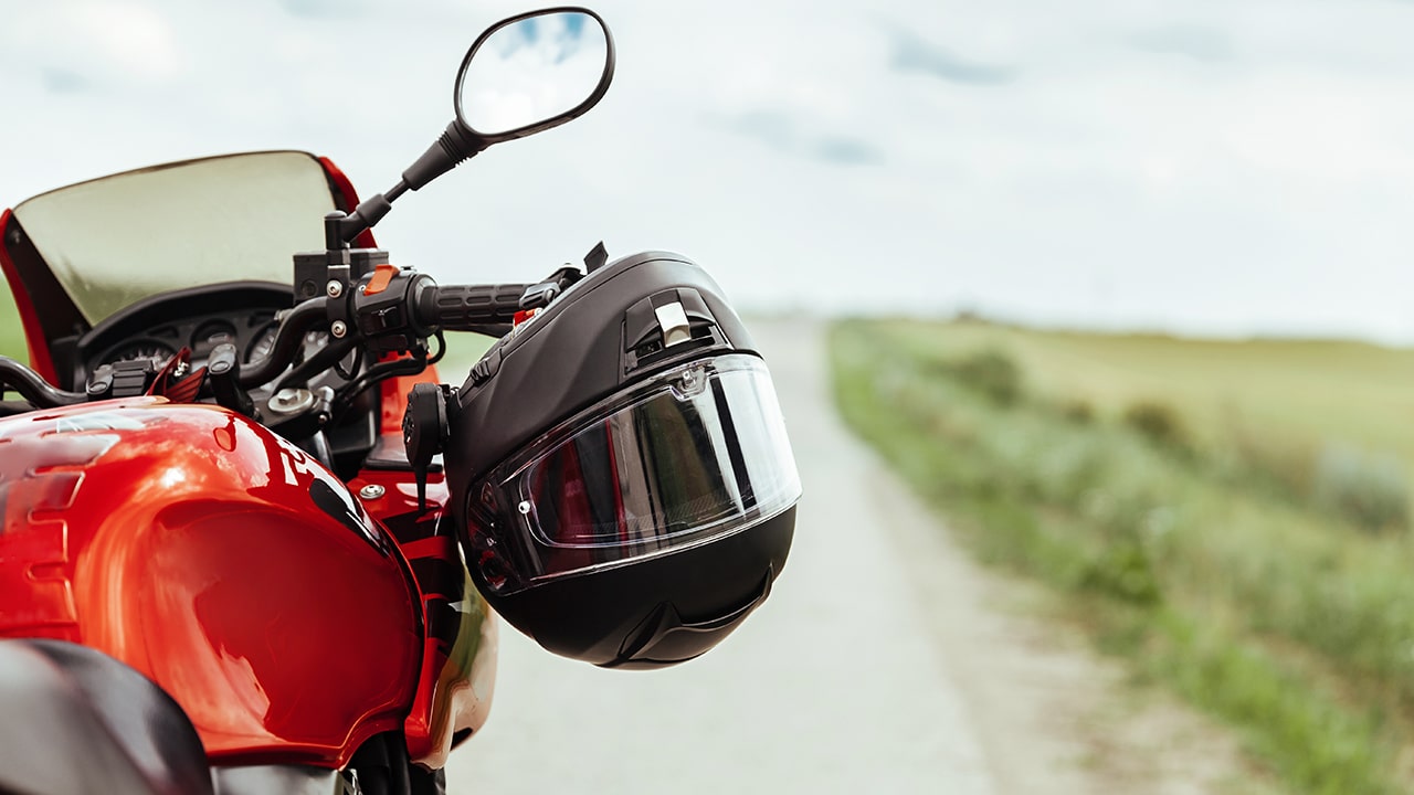 Black motorcycle helmet hanging on the handlebars of the motorcycle