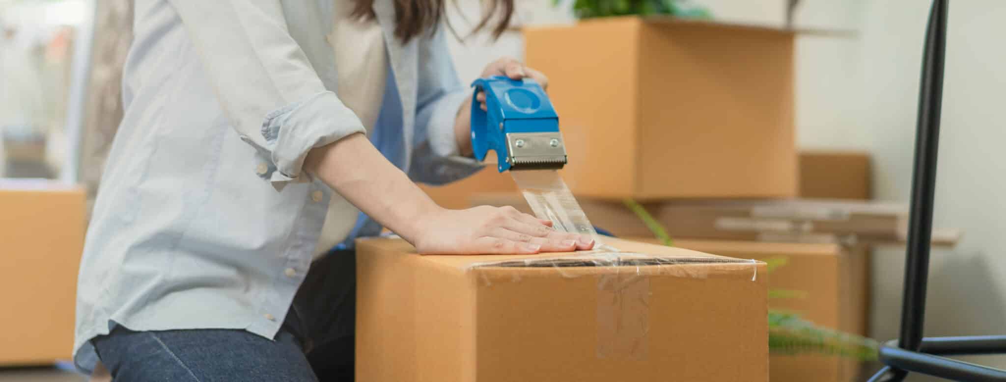 Woman packing a box with other boxes behind her.