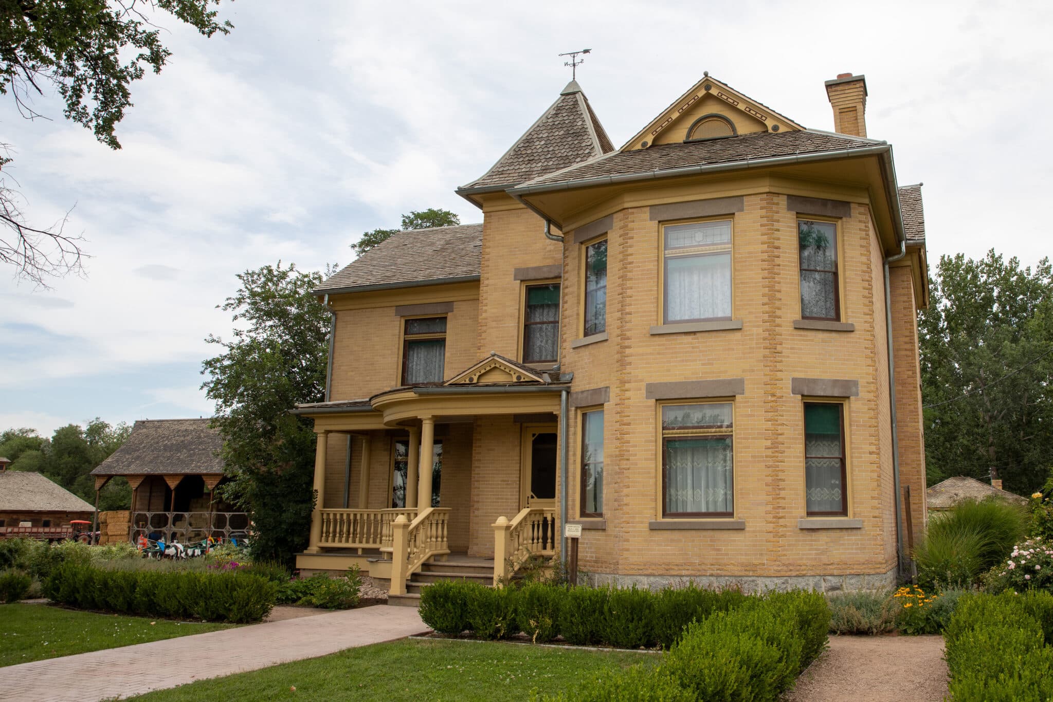 Large old house with a well kept lawn under a grey sky.