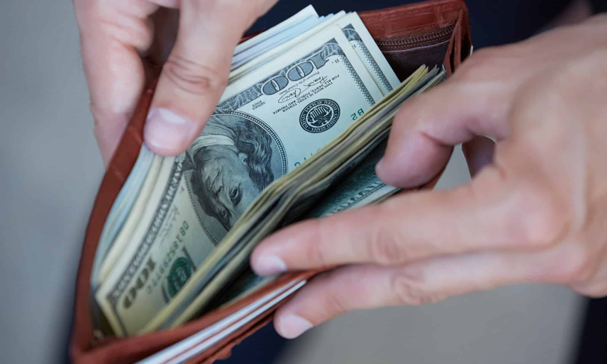 man holding a purse with money closeup