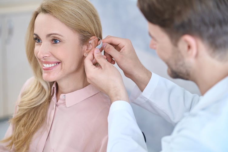 Doctor fitting hearing aids on patient