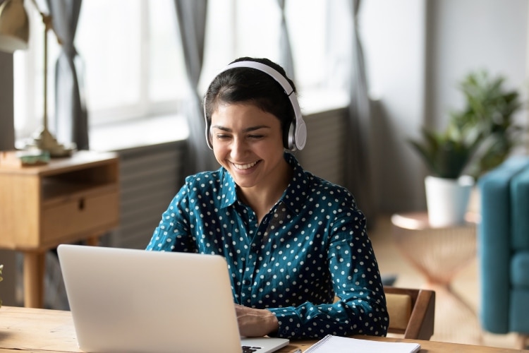 Happy woman wear headphone watch webinar listen online course communicate by conference video call e learn language in app laugh study with teacher lesson look at laptop at home