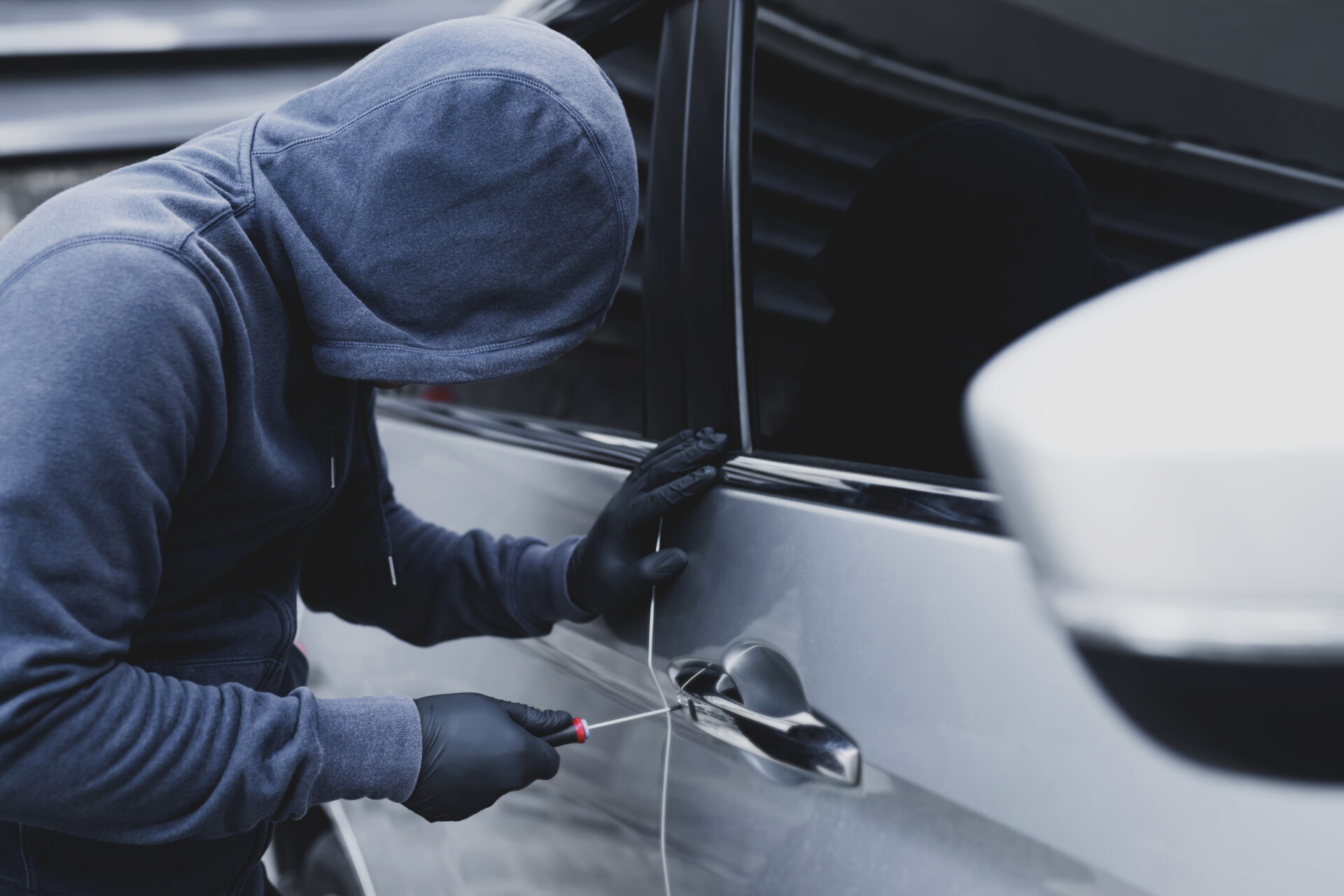 Car Thief breaking into a car with tool