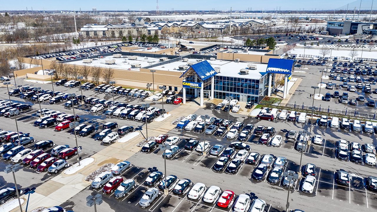 A large, one-story CarMax building sits in a giant, frosty parking lot full of cars with snow on their tops