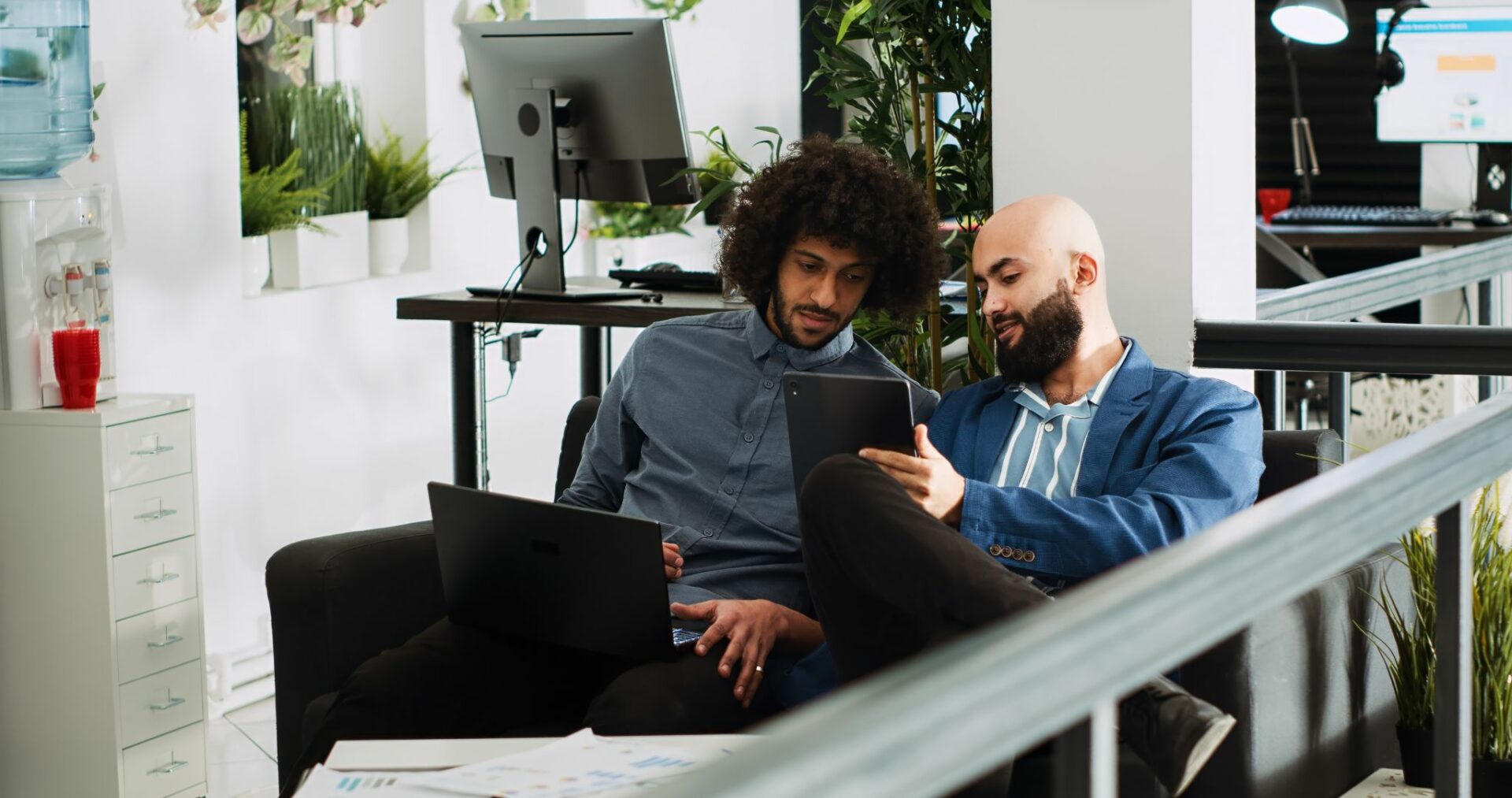 Two employee discussing something on laptop and tablet.