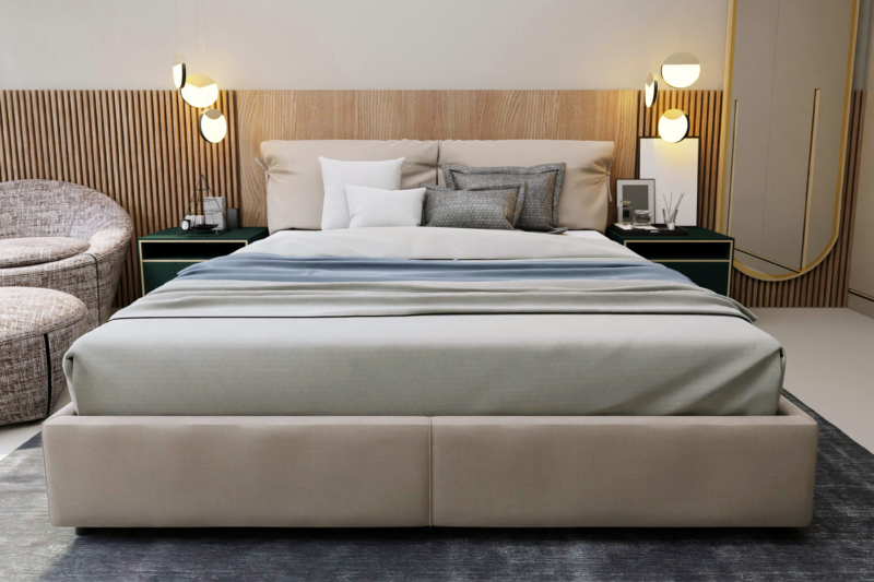 Alt text: A hybrid mattress sits on a light gray upholstered frame.