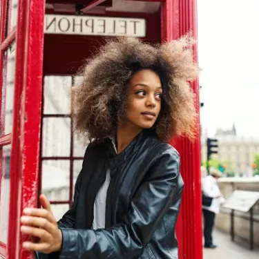 Woman stepping out of red telephone box