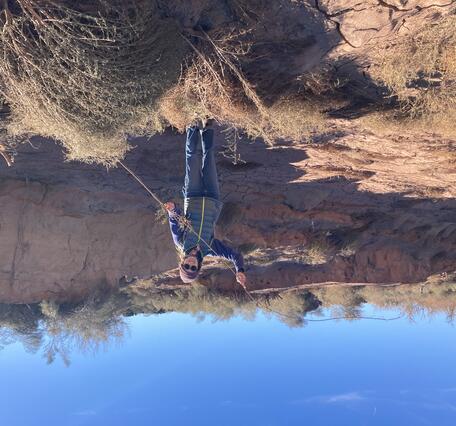 Claudia Dimartini holds a long camelthorn rhizomes exposed in a wash at Wupatki National Monument