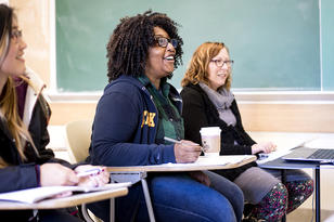 Students sitting in a classroom looking excitedly at the instructor (not pictured)