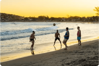 Curtindo o feriado: partida de futebol na praia ao entardecer.