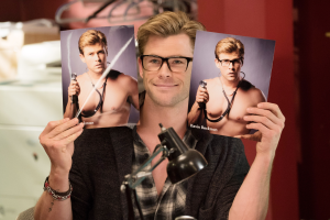 Chris Hemsworth holds up two headshots in GHOSTBUSTERS.