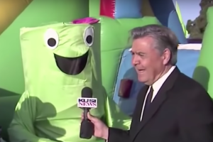 News anchor Dave Scott interviews a green inflatable mascot.