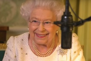 Queen Elizabeth smiling behind a microphone