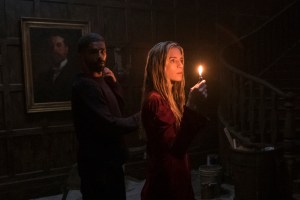 Brit Marling in THE OA PART 2 a woman in a red dress in a dark room holding a candle