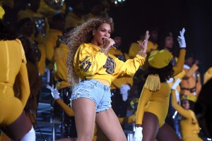 Beyonce in a yellow sweatshirt on stage at Coachella 2018