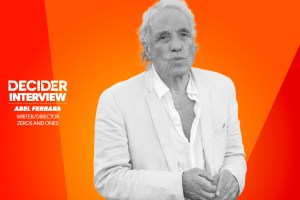 ABEL FERRARA in black and white in front of a bright orange background