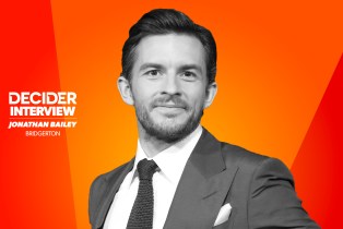 Jonathan Bailey in black and white in front of a bright orange background