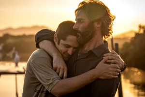 Two men hugging in front of a bright sun