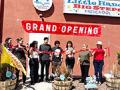 a group of people holding a banner that reads "Grand Opening"