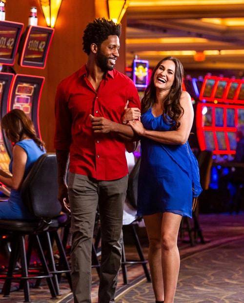 Couple walking through slot machine area within Red Hawk Casino