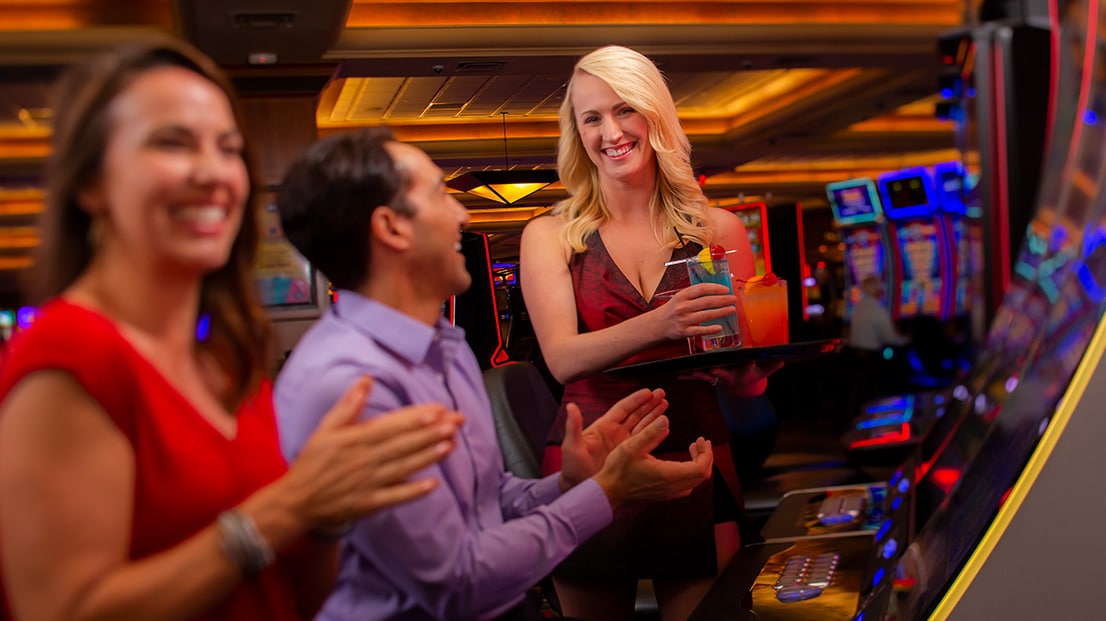 Bartender delivering drinks to guests playing slots