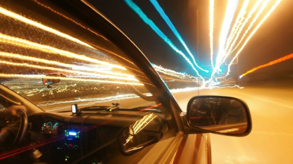 Decorative image of a car driving at night with light streaks.