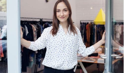 Young woman posing in front of closet, smiling.