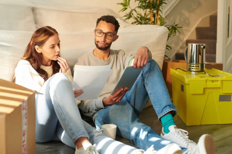 two people sitting on the floor going over their moving budget