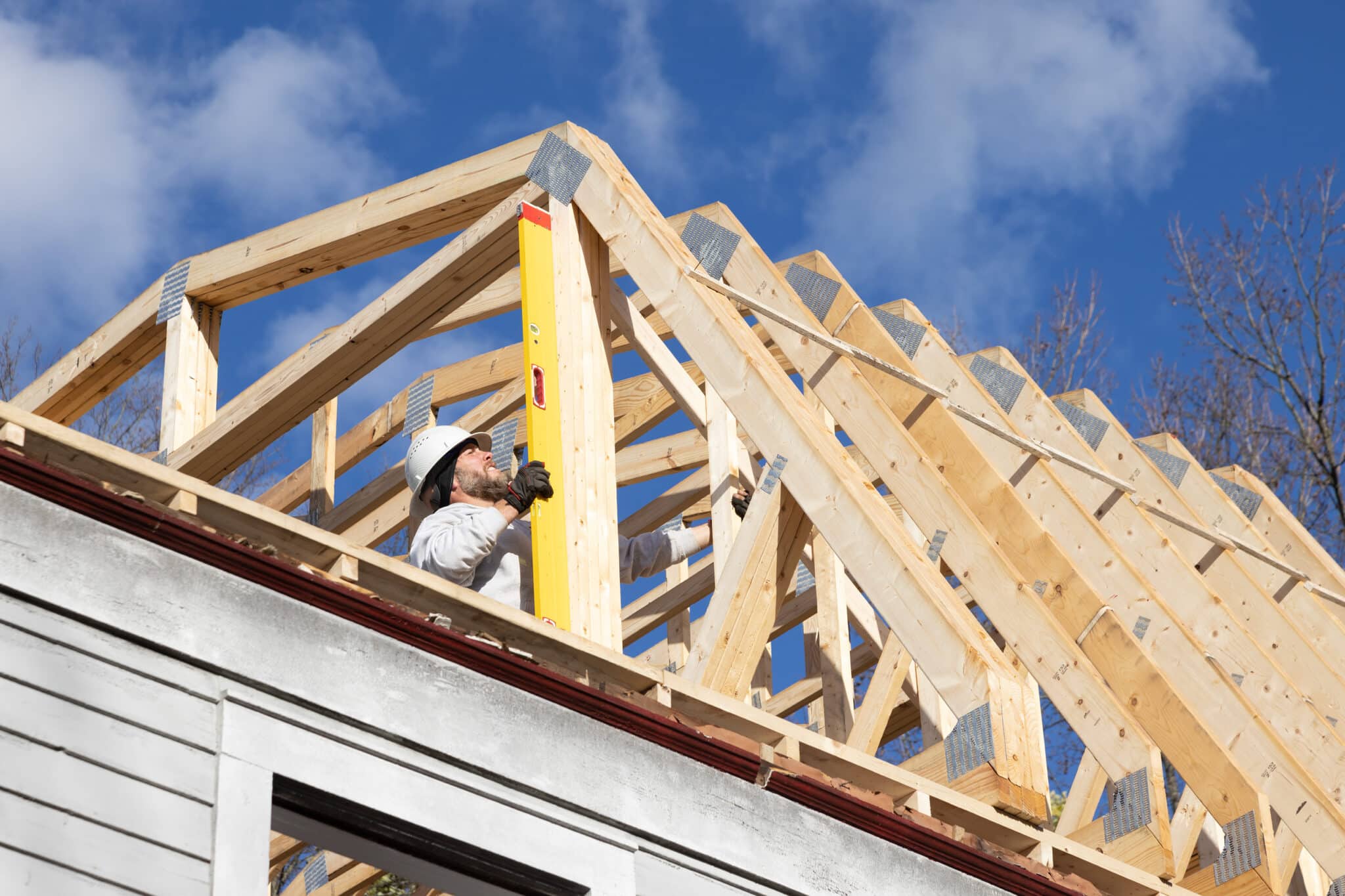 Man making sure a beam on a roof truss is strait.