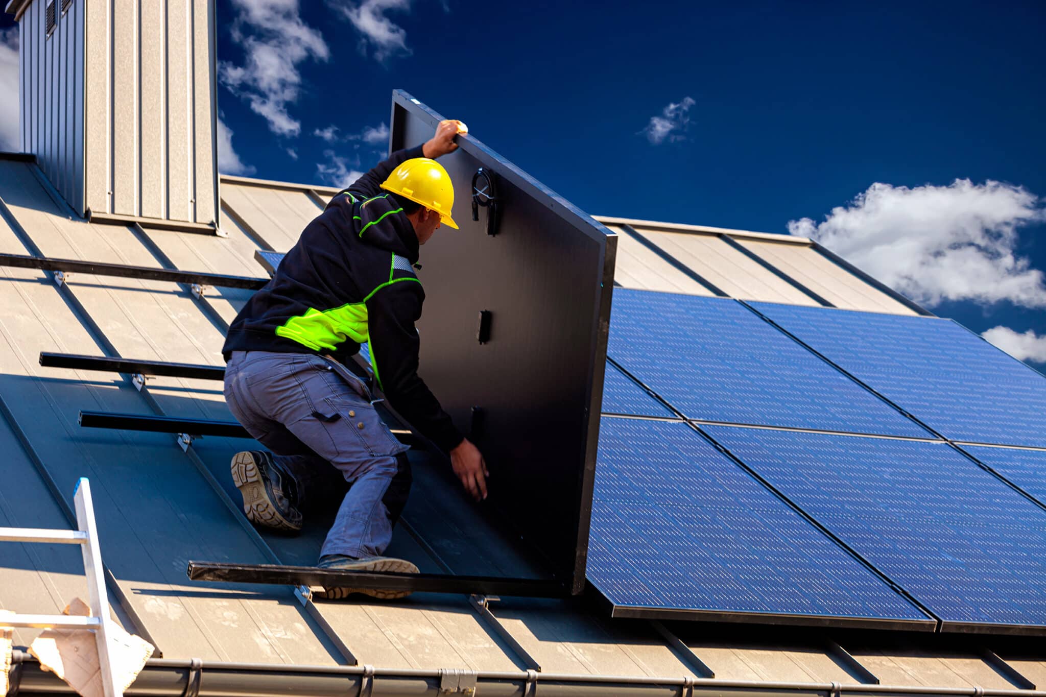 Man putting up solar panels on top of a house