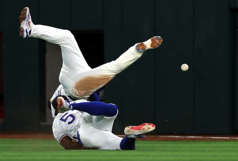 Texas Rangers second baseman Marcus Semien (2) and right fielder Adolis Garcia (53) collide...