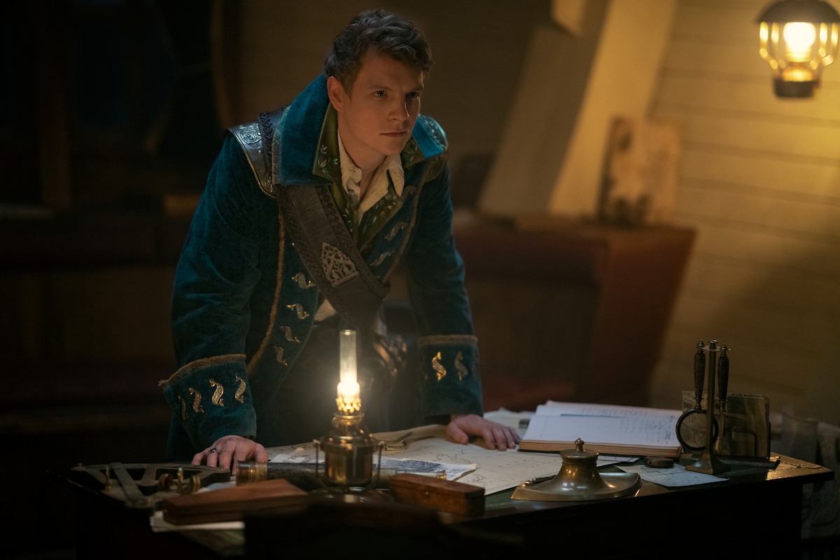 Patrick Gibson in a teal pirate's jacket as Nikolai 