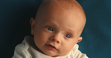 A baby laying on blue bedding.