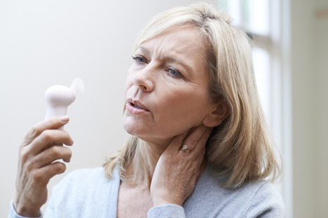 A photo of a middle-aged woman holding an electric an to her face. 