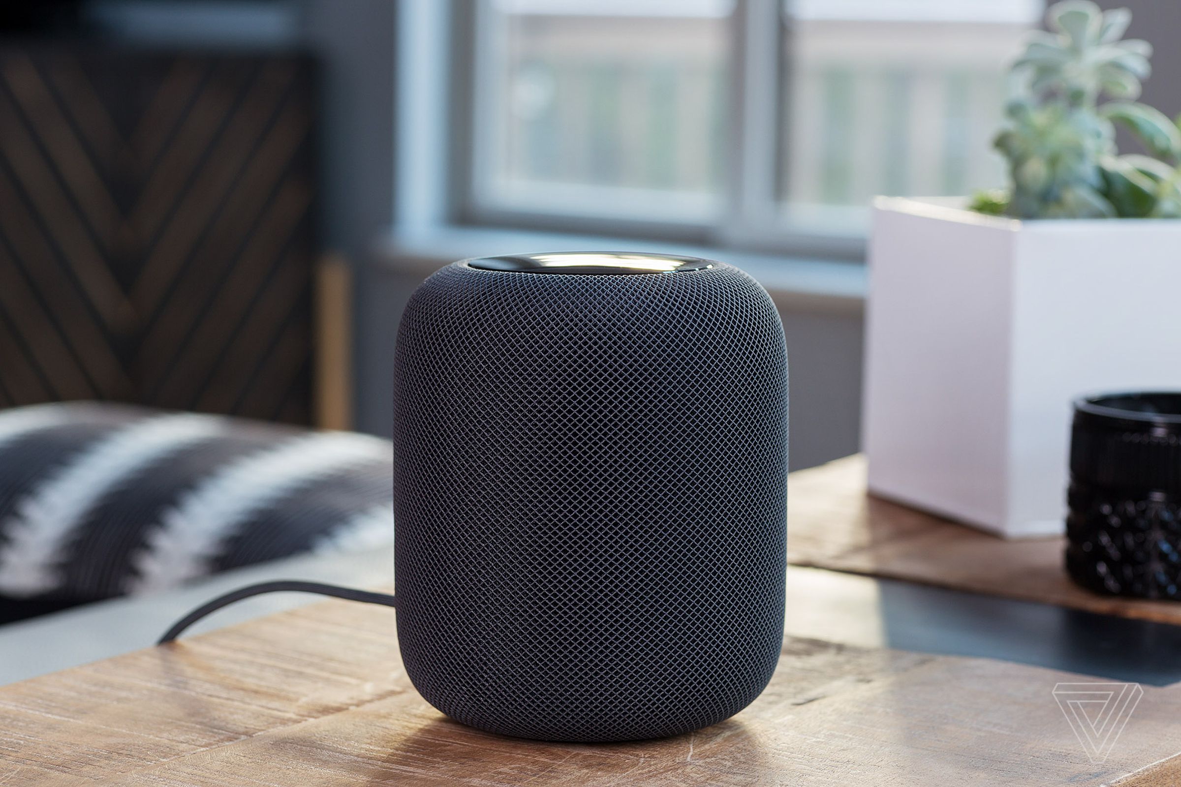 A first-generation HomePod on a desk in a room.