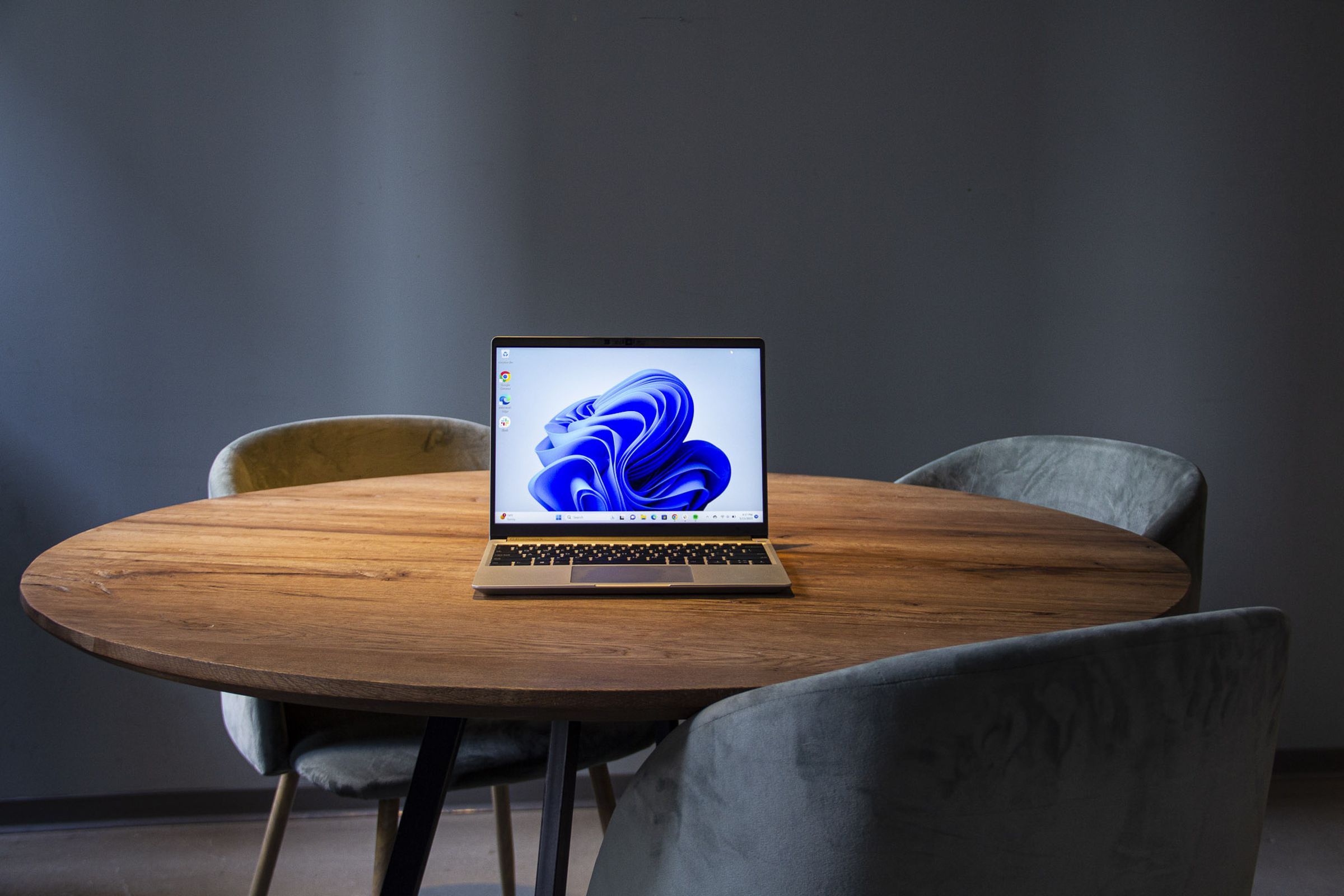 Framework Laptop 13 on a wooden table displaying a blue desktop background.