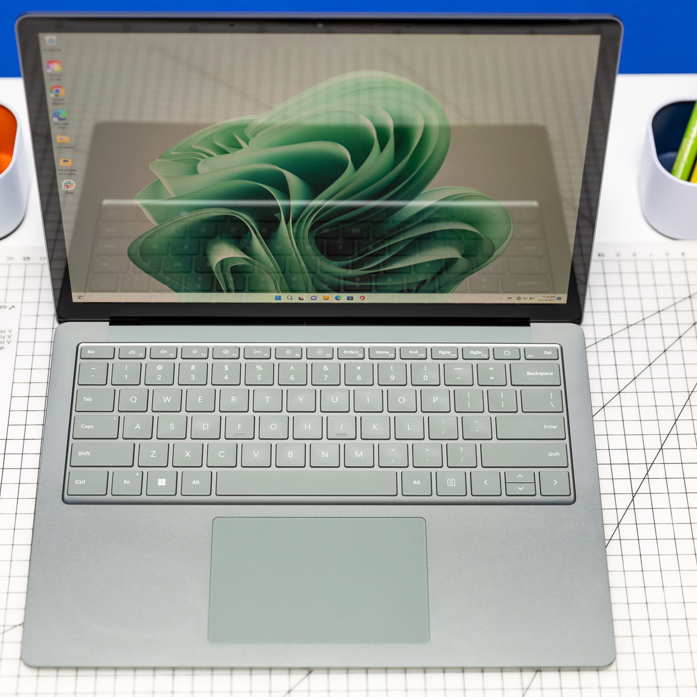 The Surface Laptop 5 seen from above, open, on a desk with Post-its and pencils. The screen displays a green ribbon.