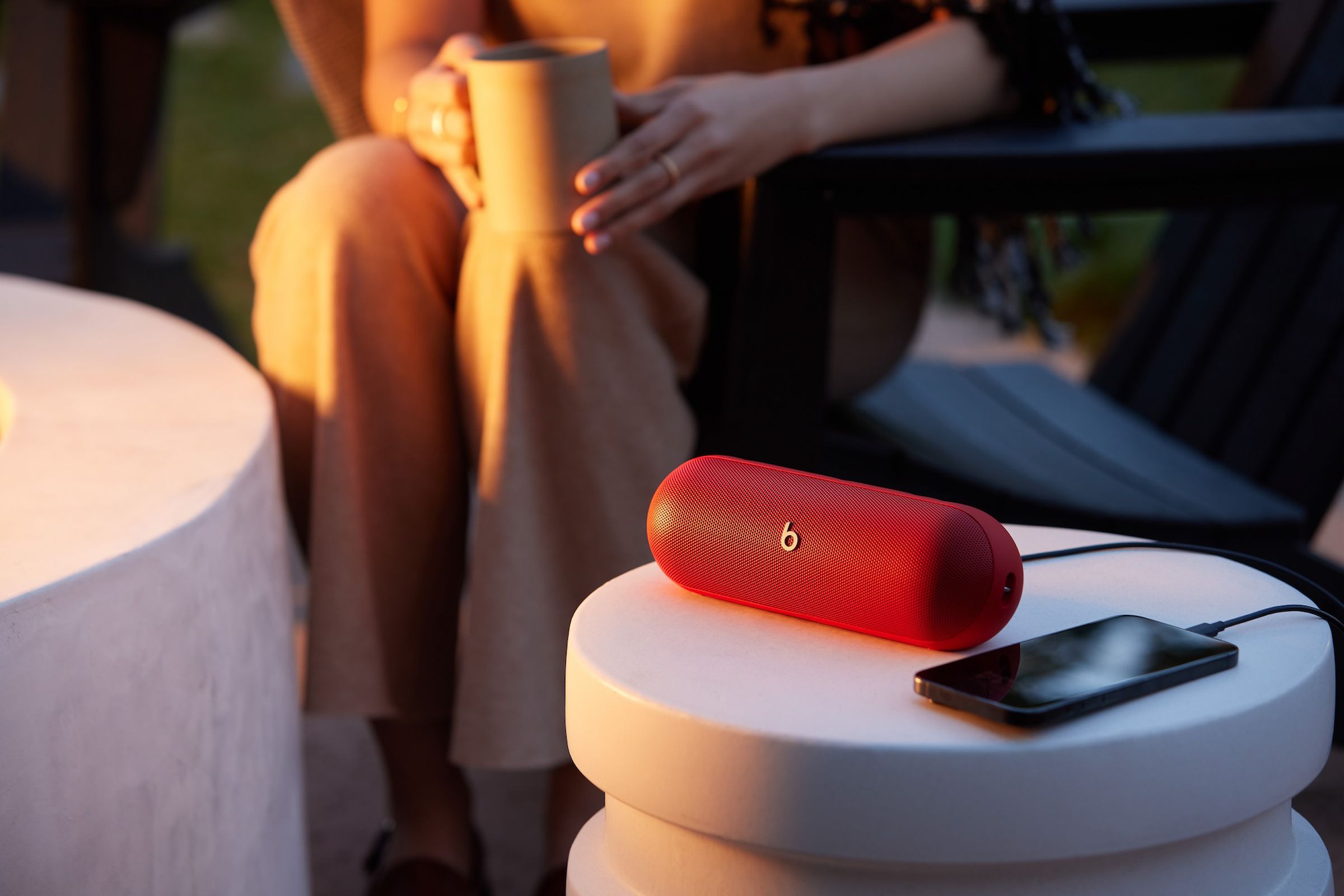 A marketing image of the Beats Pill speaker with someone holding a coffee mug in the background.