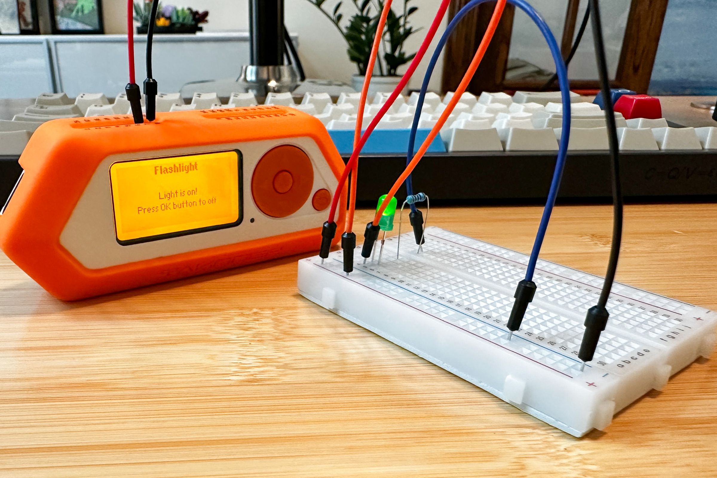 Photo of a Flipper Zero connected to an electronics breadboard with several wires. a lit-up green LED and a resistor are also connected to the breadboard.