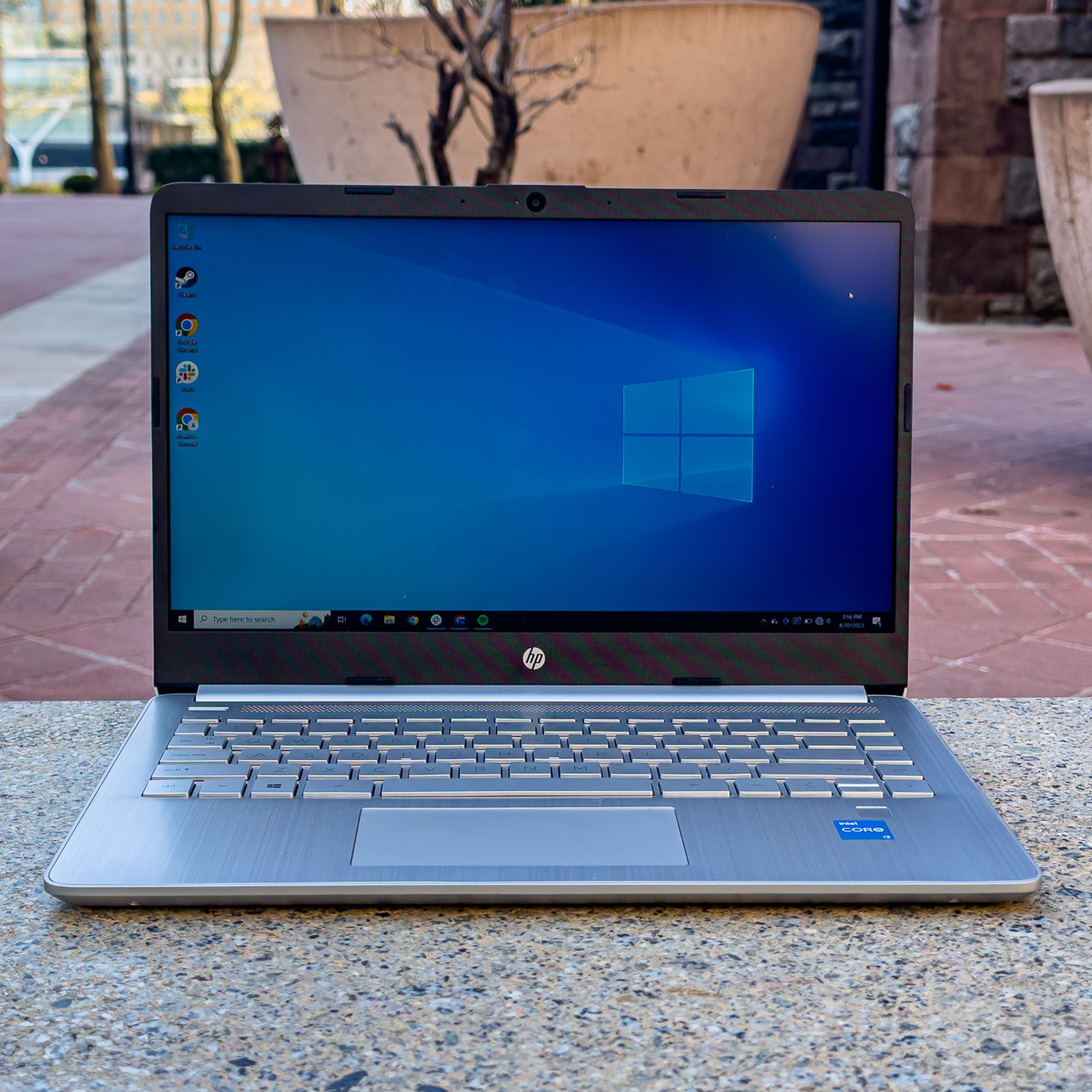 The HP 14 open in an outdoor setting displaying the Windows default desktop background.