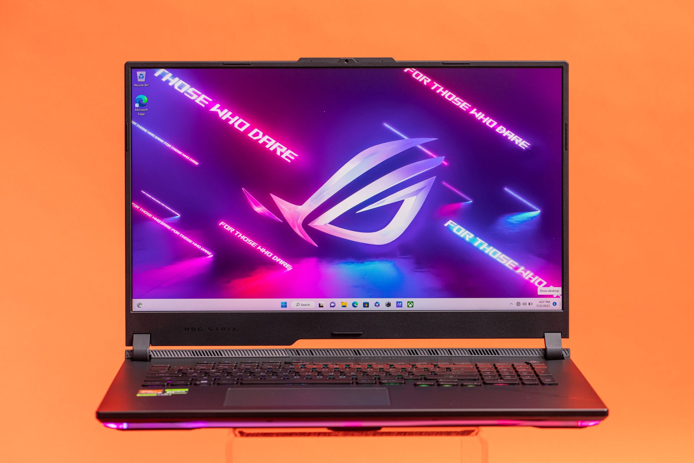 The Asus ROG Strix Scar 17 on an orange background displaying a desktop with the ROG Logo that reads “Hard Drive”.
