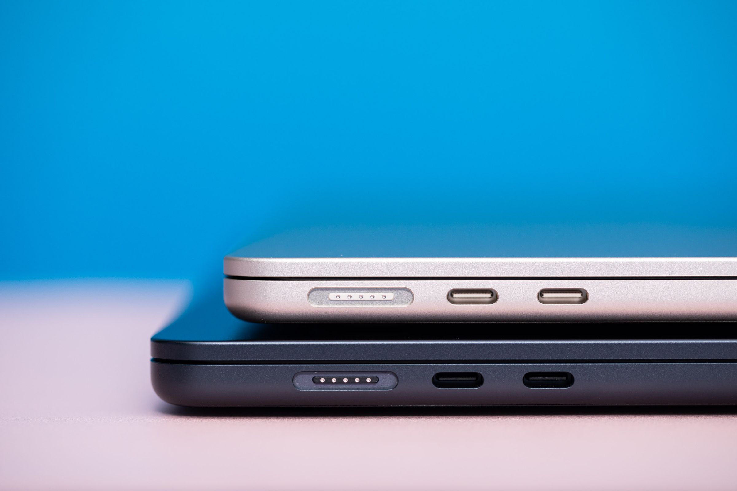 A close up of the side of two laptops, stacked, showing connectivity ports.