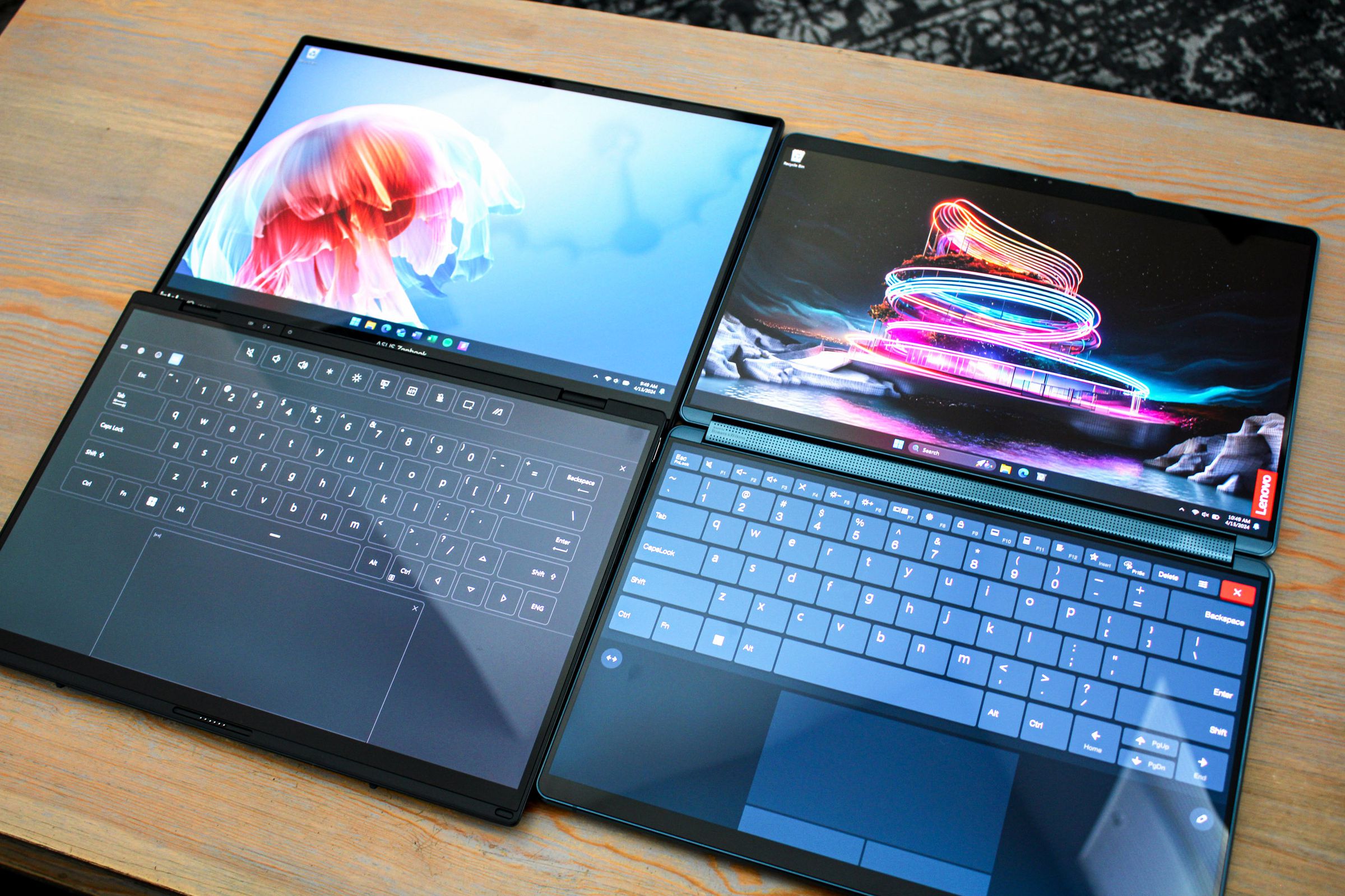 Two laptops laying flat side by side on a wood table.