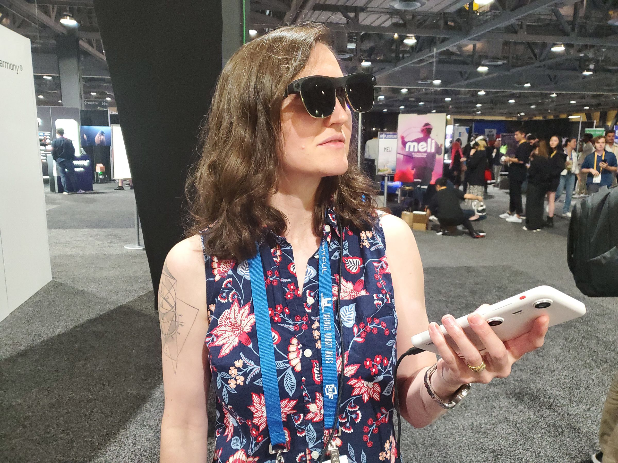 A brown-haired woman wearing Xreal’s AR sunglasses, holding the Beam Pro as a controller.
