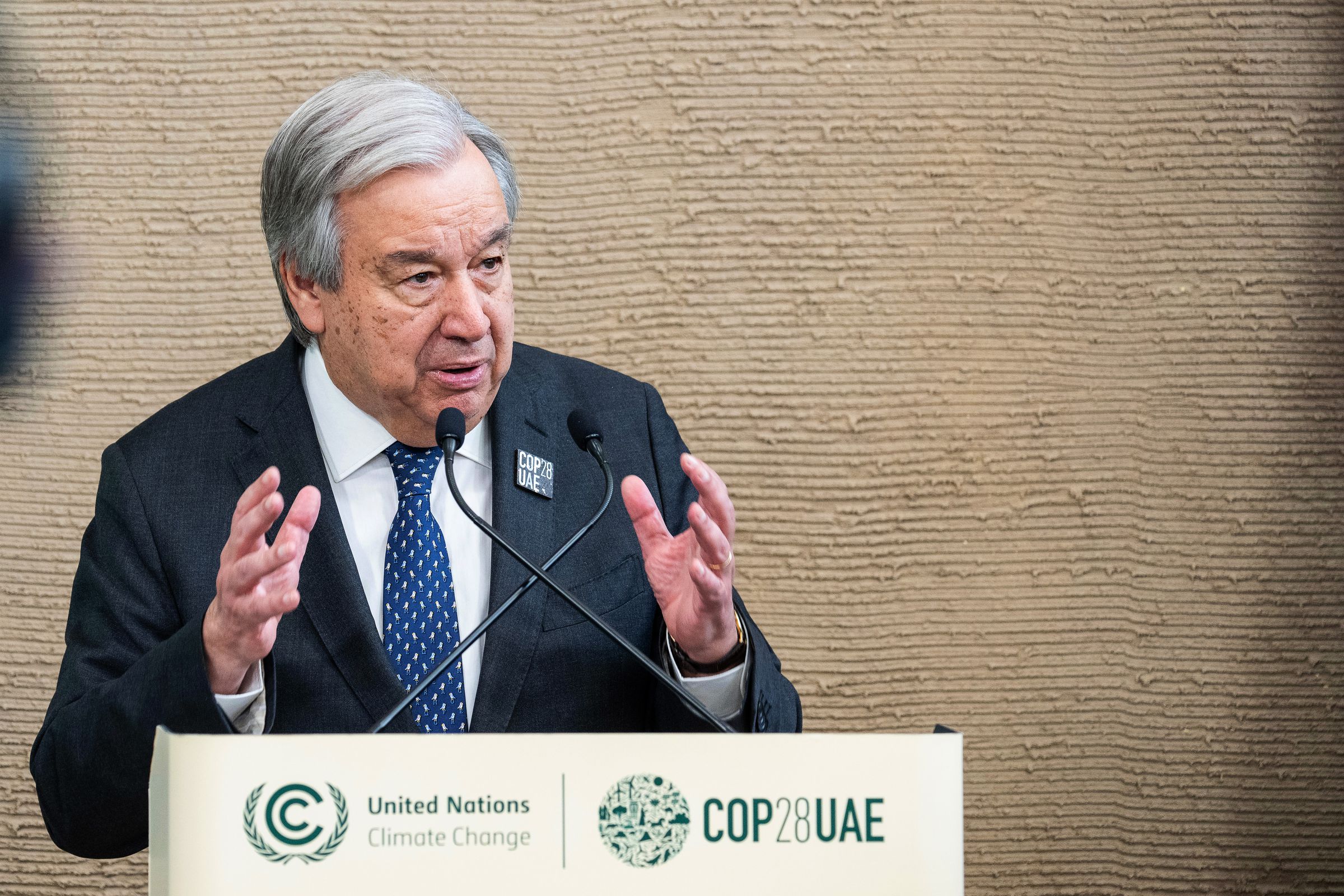 A photo of an older man speaking at a podium.