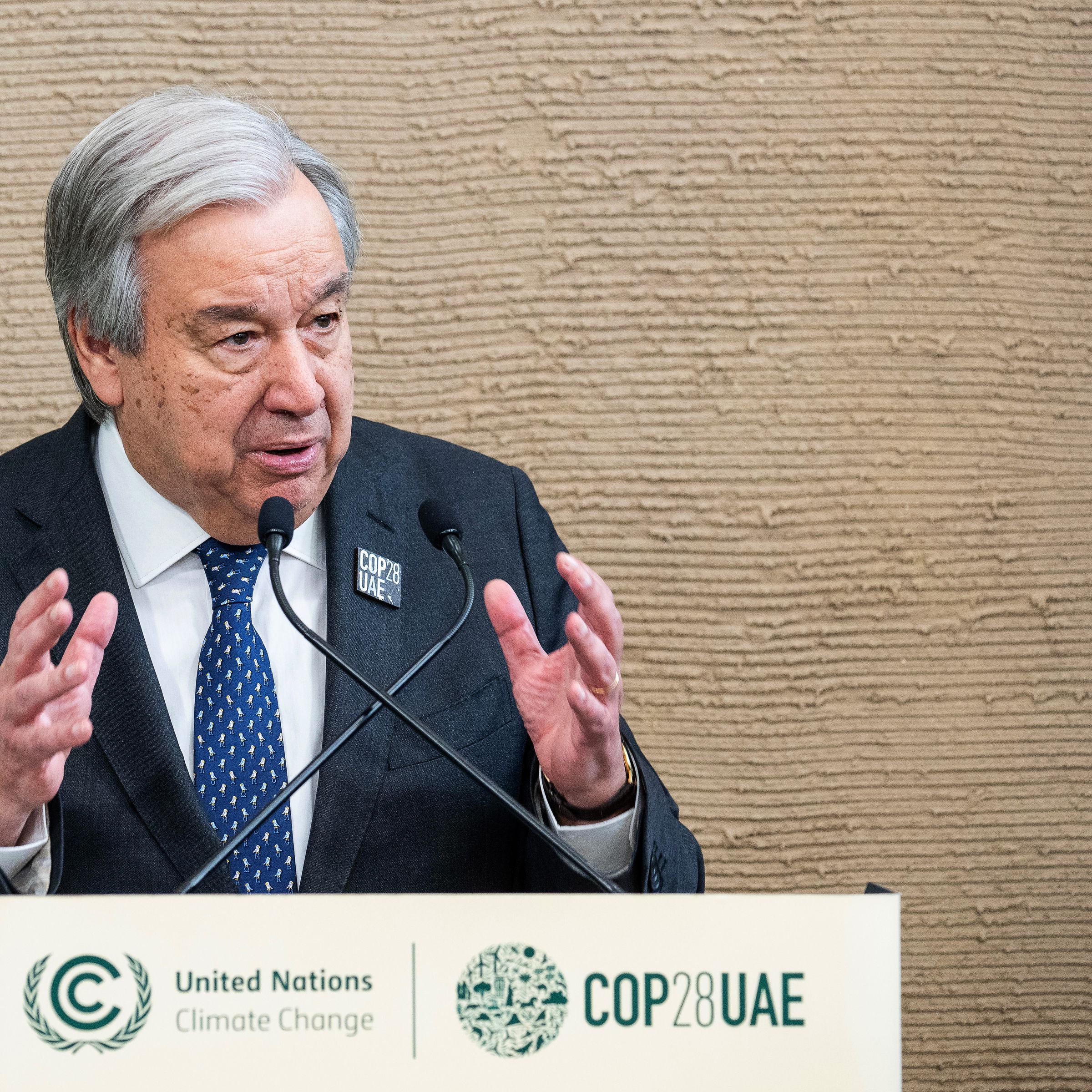 A photo of an older man speaking at a podium.